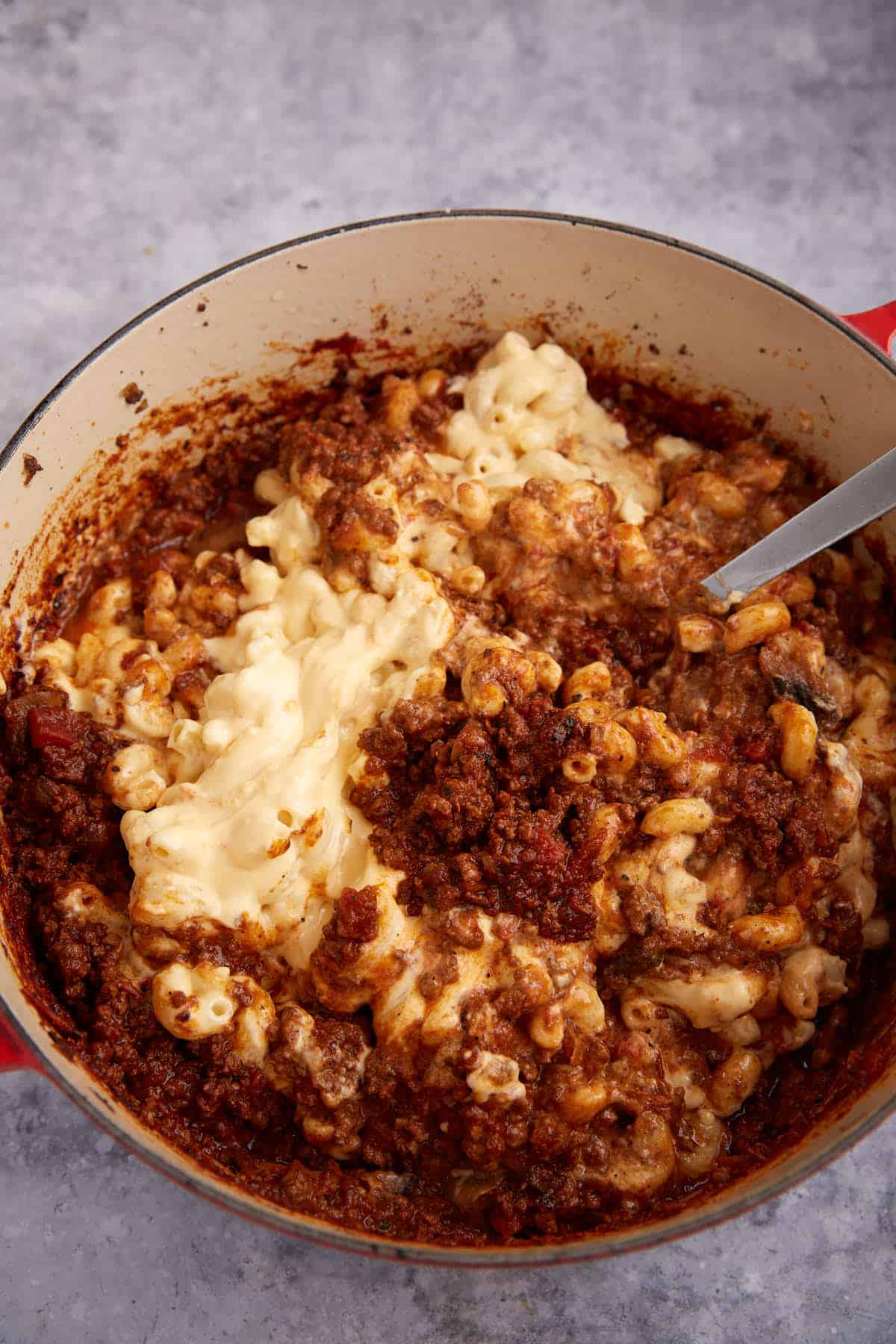 Mac and cheese being folded into chili.
