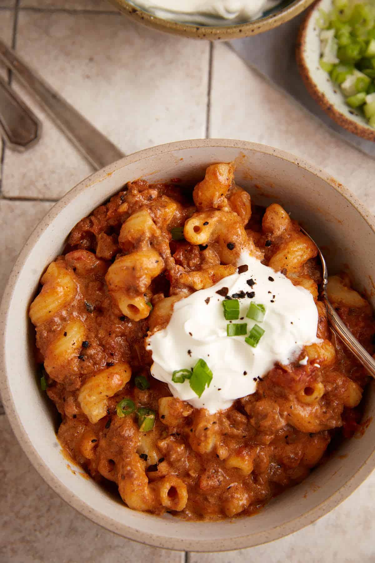 A bowl of chili mac topped with sour cream.