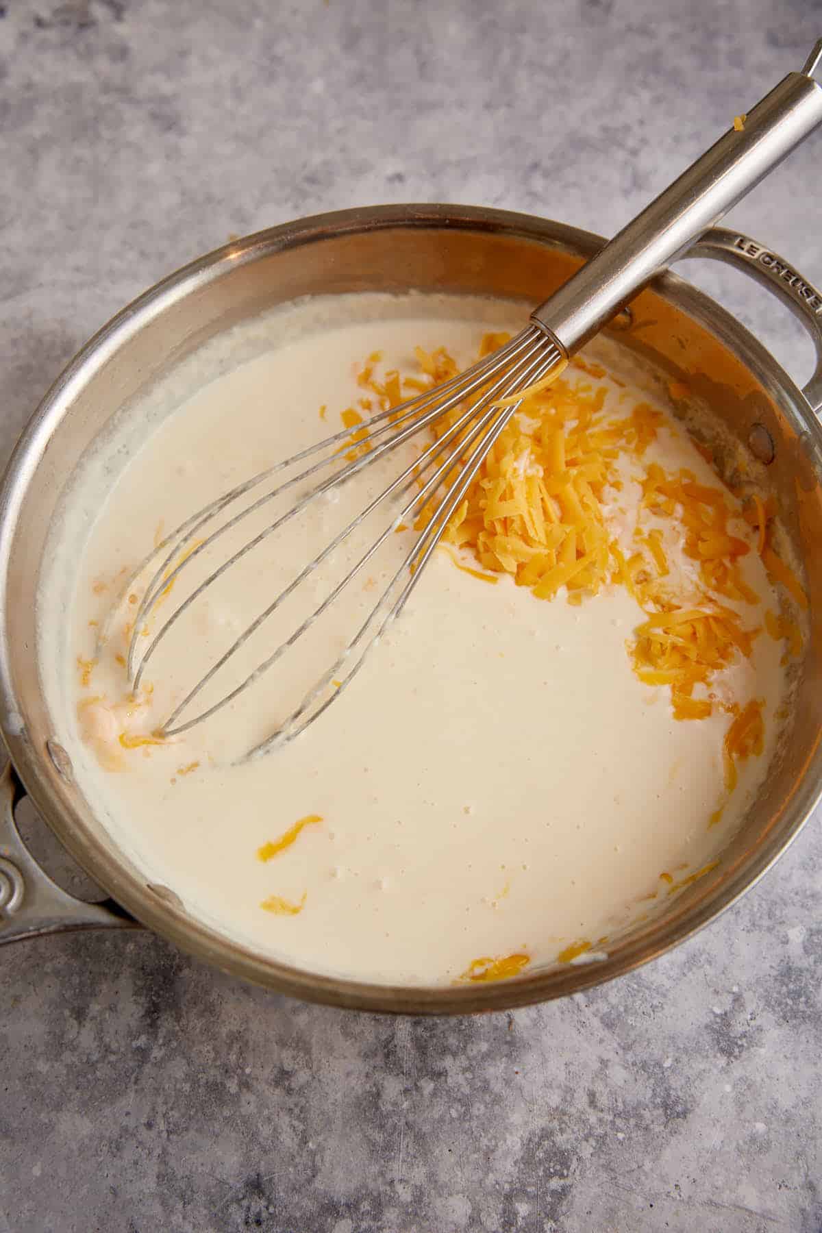 Cheese added to the white sauce in a saucepan.