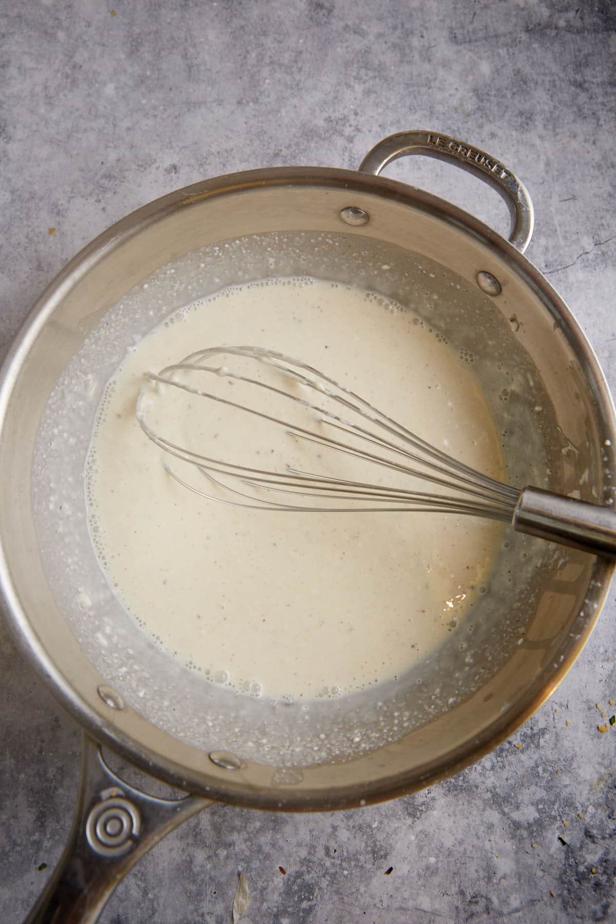 A saucepan with milk and a whisk.