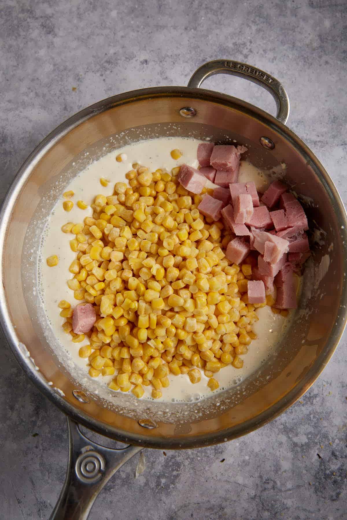 Corn and ham added to a saucepan.