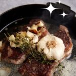 Steaks in a skillet with garlic and butter.