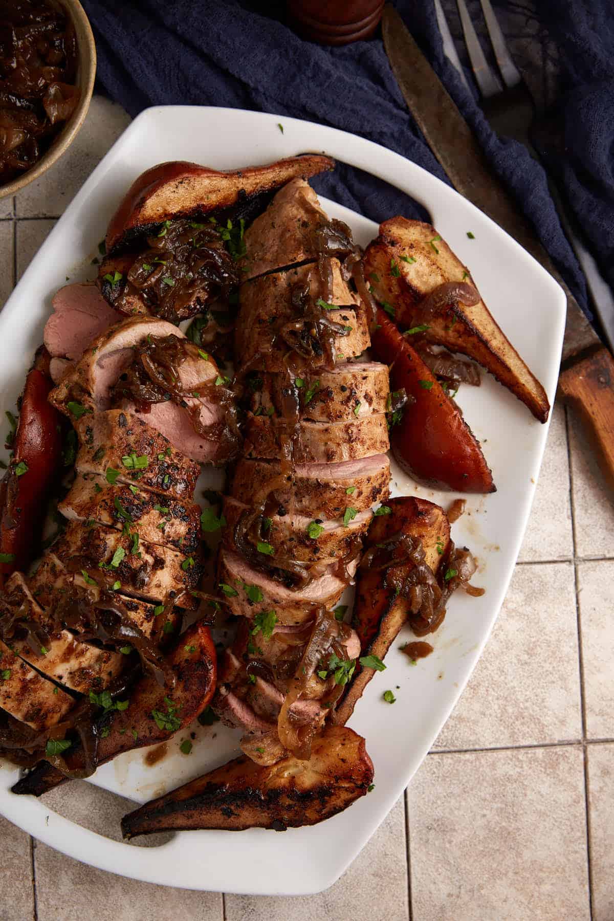 Sliced pork tenderloin with pears on a platter.