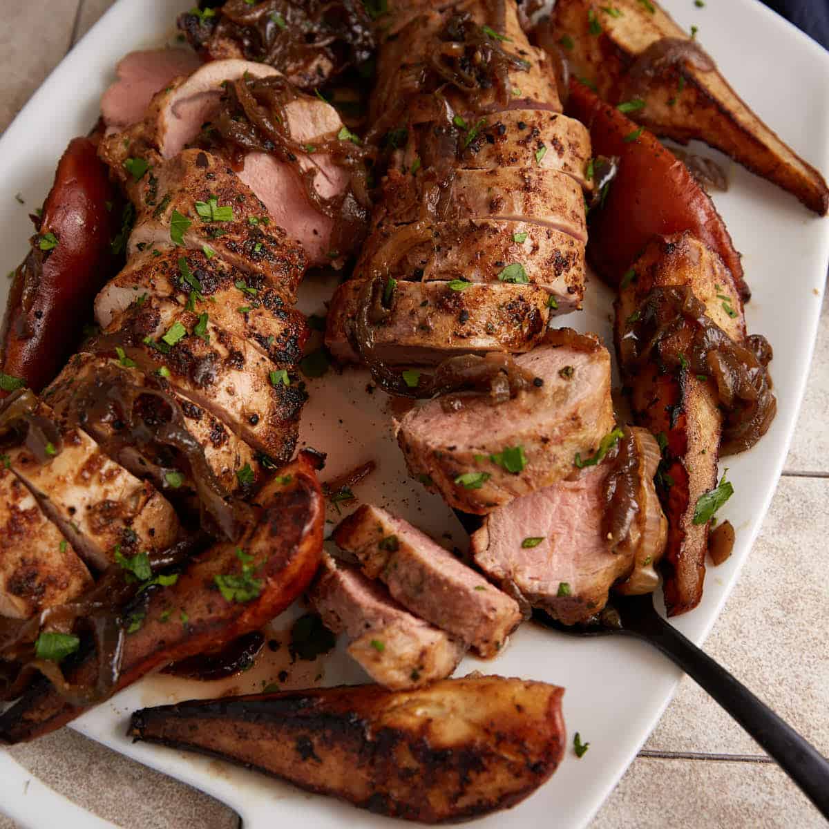 Roasted pork tenderloin with caramelized onions and pears on a serving platter.