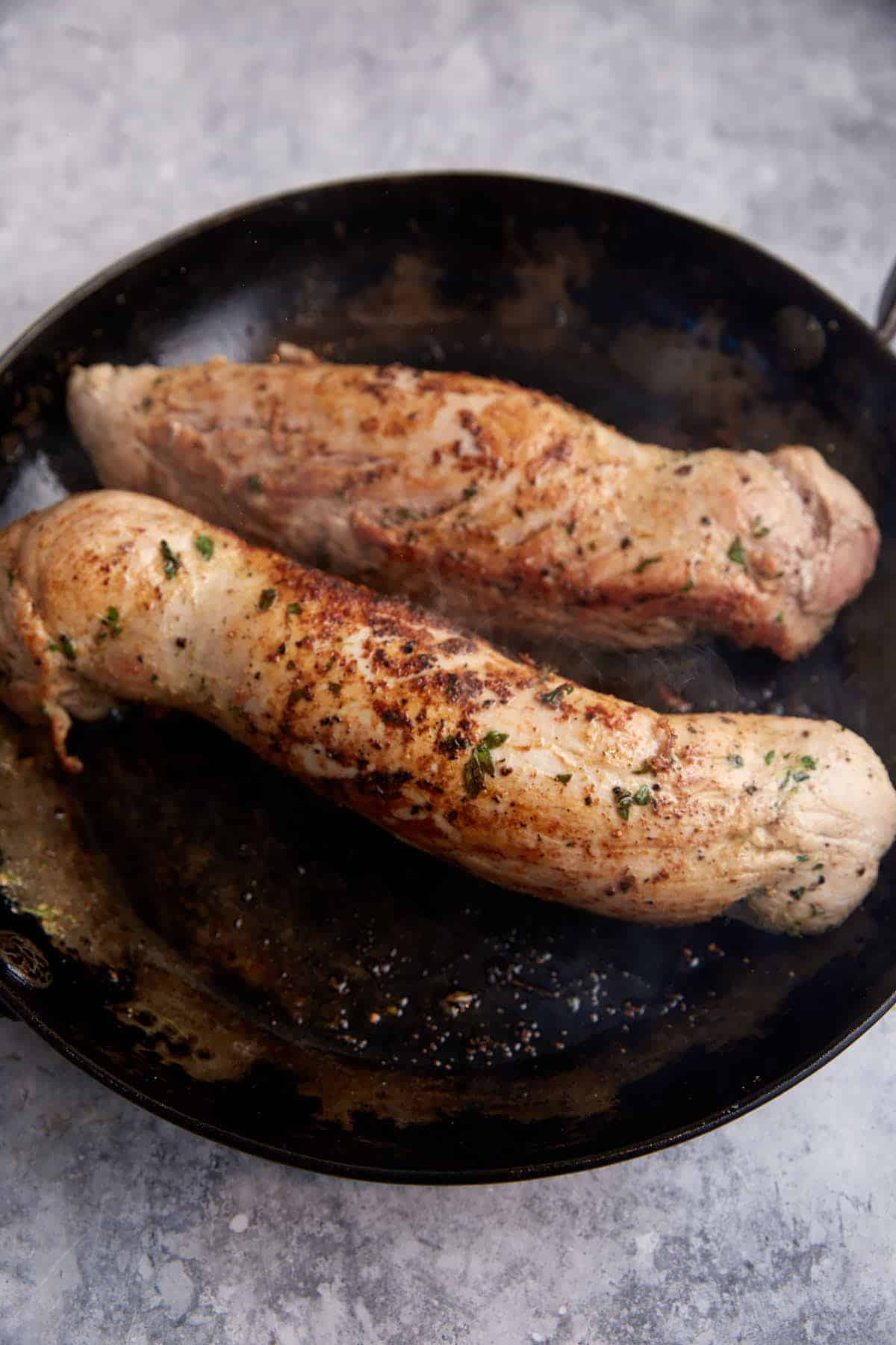 Seared pork tenderloins in a skillet.