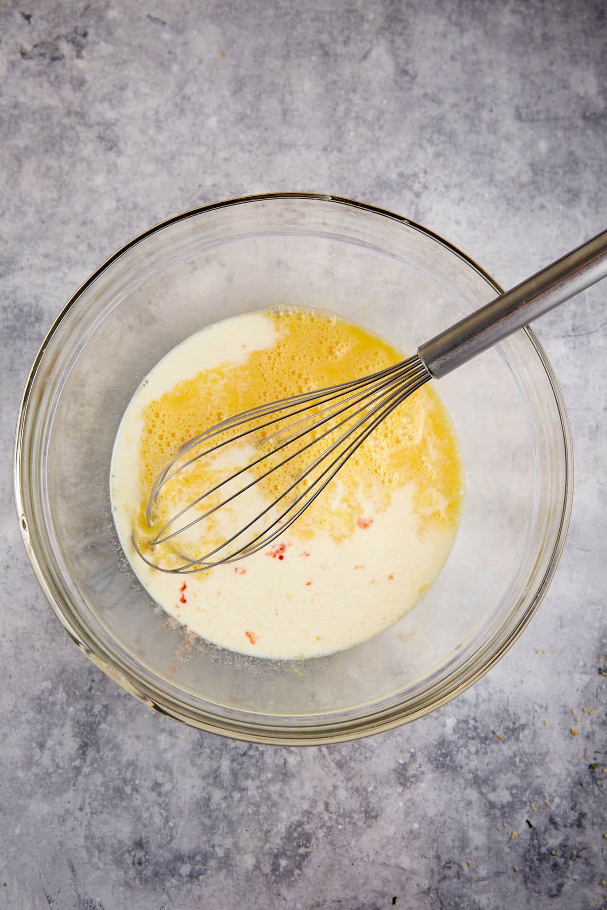 Eggs and milk in a bowl with a whisk.