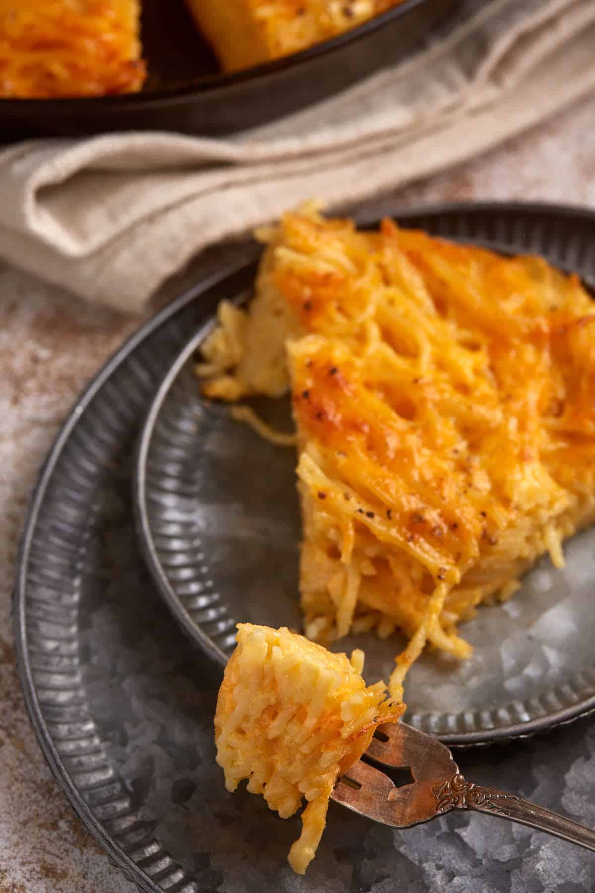 A piece of spaghetti pie with a bite on a fork.