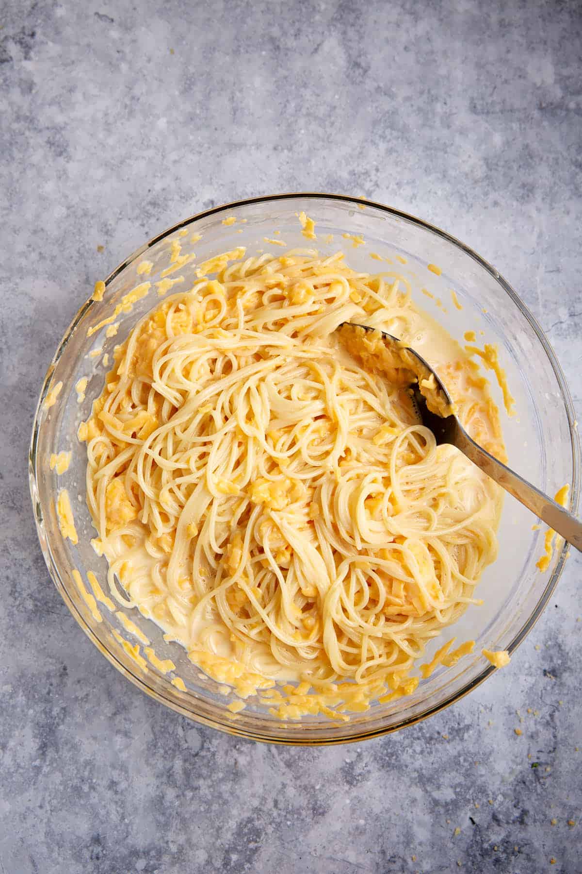 Cheese added to a bowl of spaghetti pie.