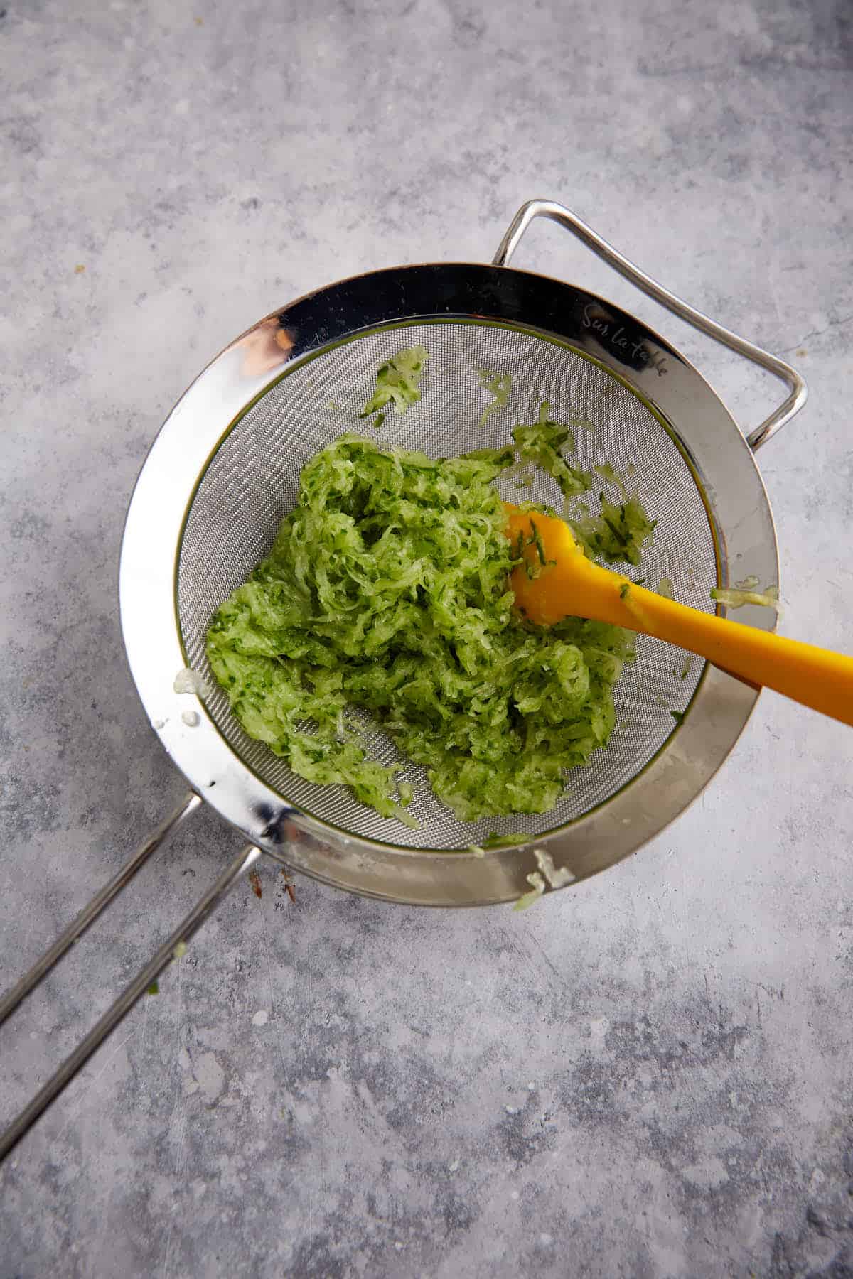 Grated cucumbers in a sieve.