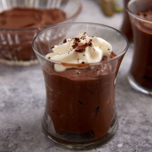 A single glass of chocolate pudding topped with whipped cream.