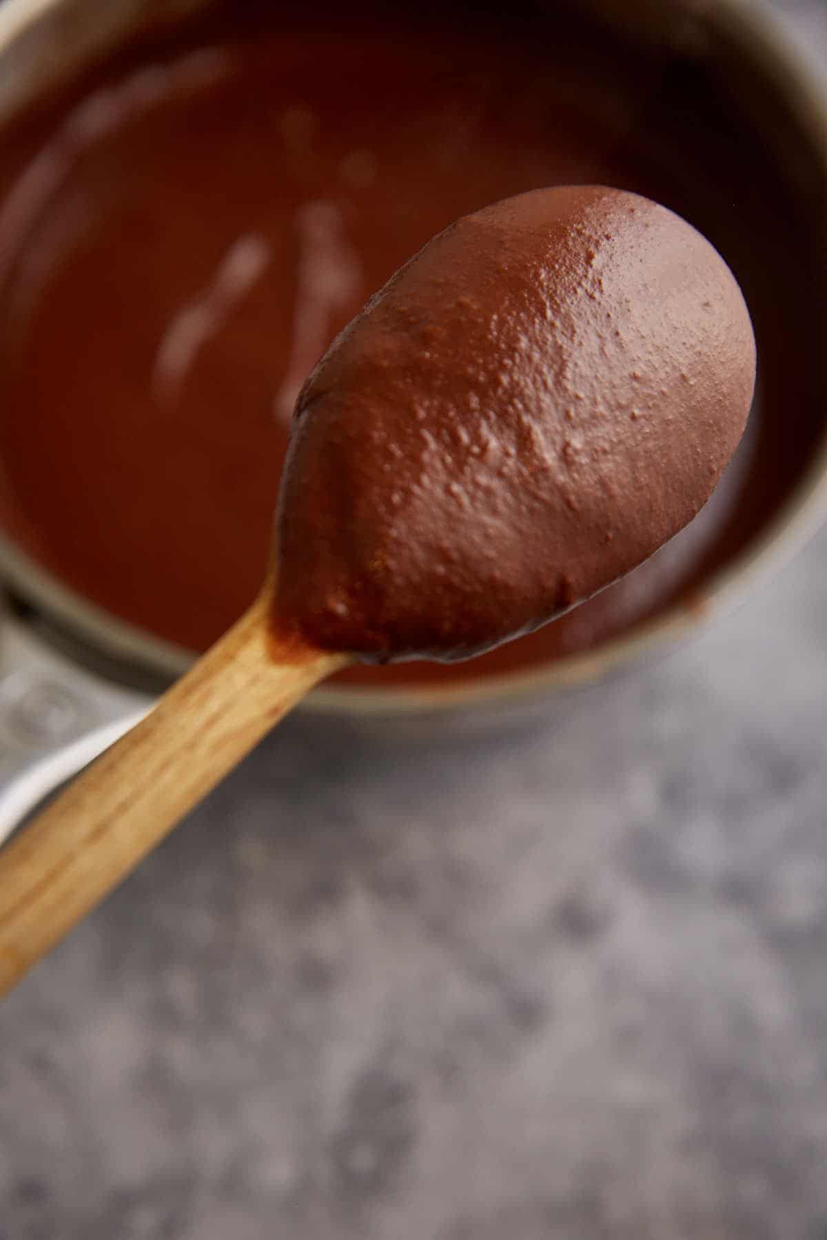 A spoon coated in chocolate pudding.
