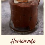 A dessert glass of chocolate pudding topped with whipped cream.