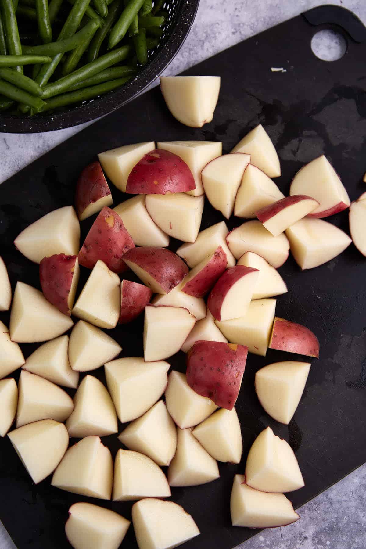 New potatoes chopped on a cutting board.