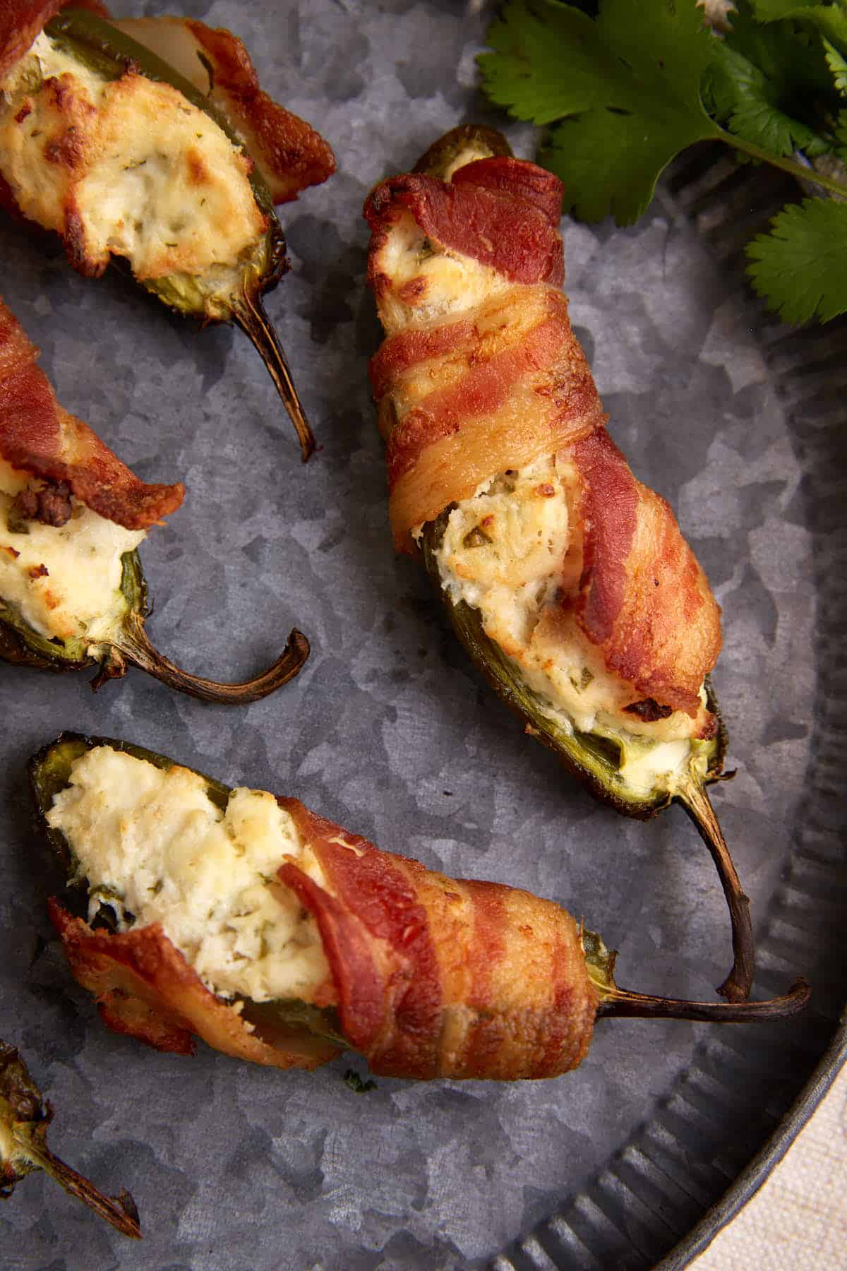 Two jalapeno poppers on a plate wrapped in bacon.