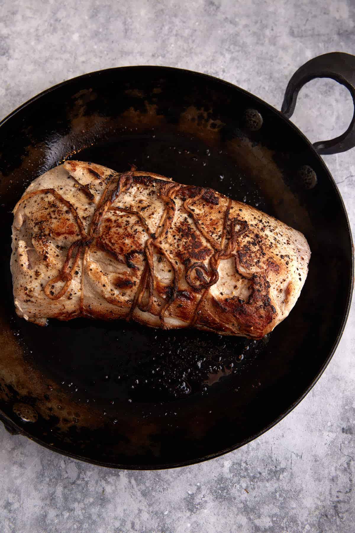 A pork loin browned in a skillet.