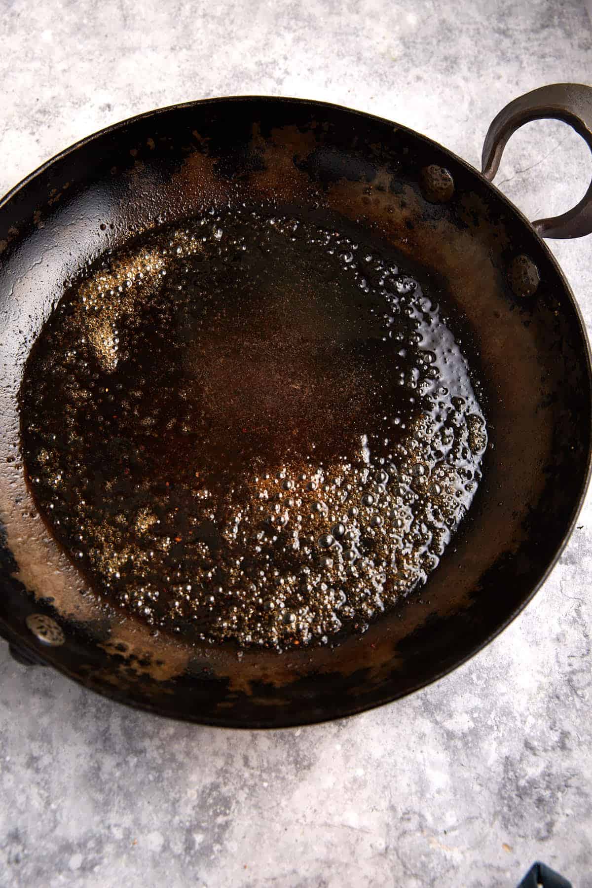 A maple glaze cooking in a skillet.