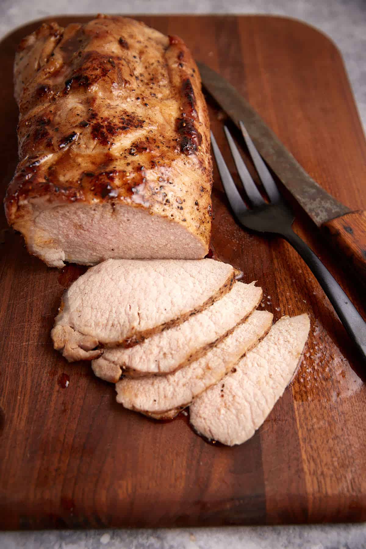 A pork roast that has been sliced on a cutting board.