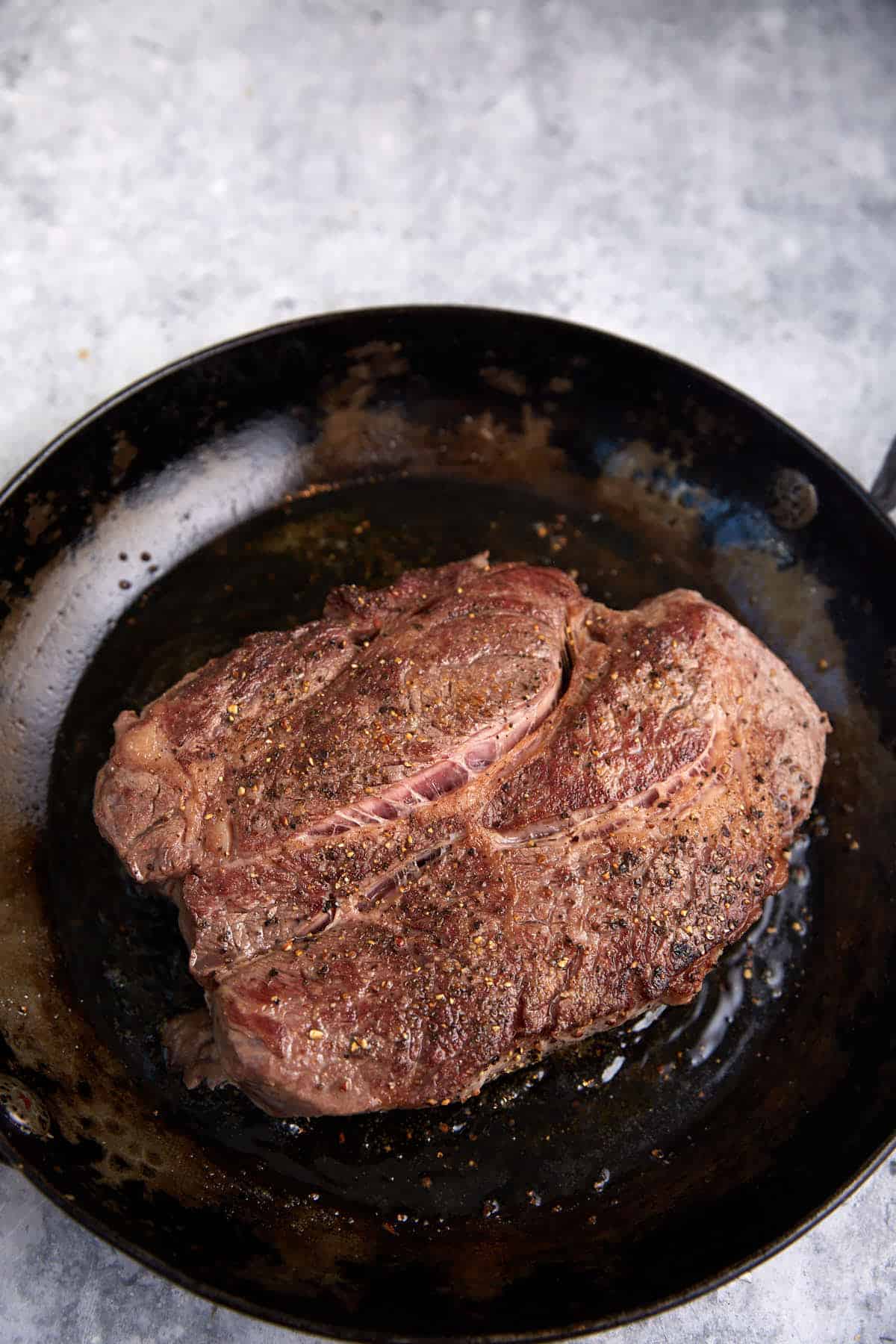 A browned chuck roast in a skillet. 