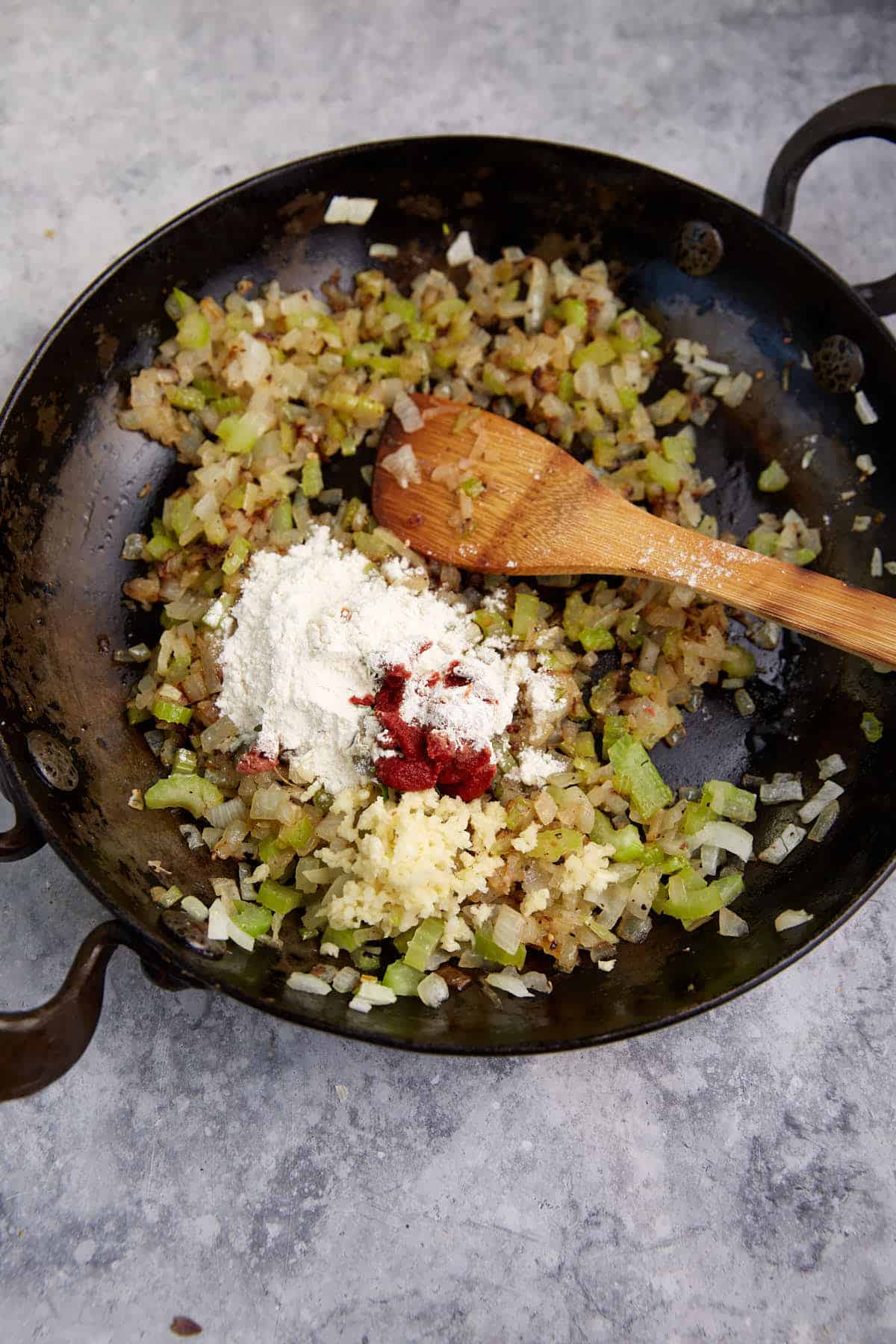 Flour added to a skillet with onions and celery. 