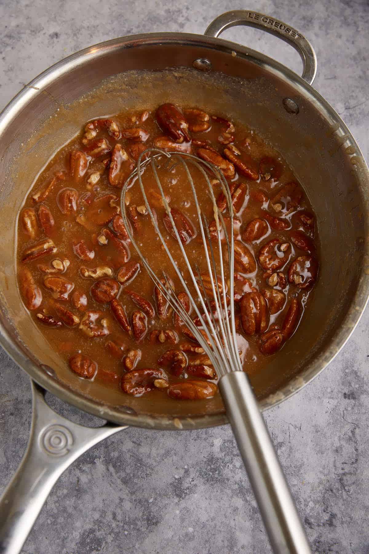 Pecans added to caramelized sugar in a saucepan.