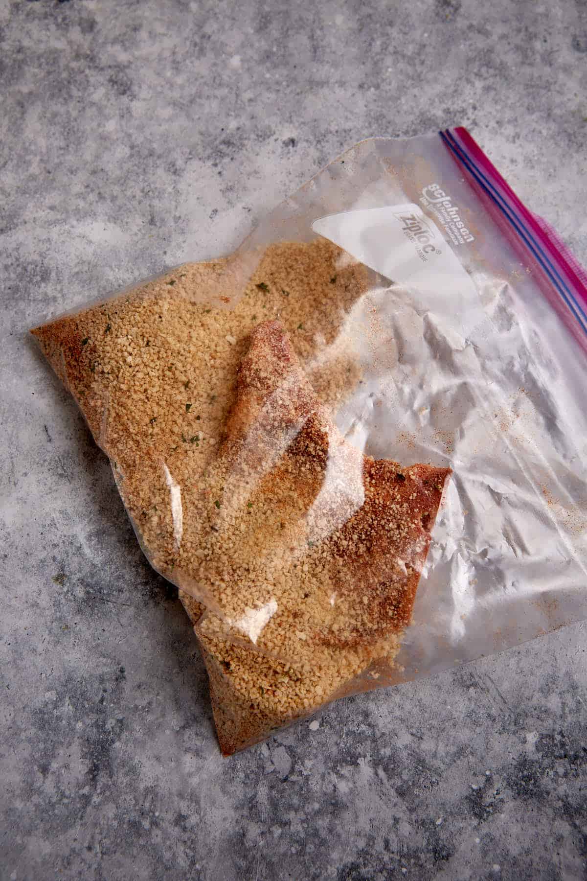 A pork chop in a ziplock with seasonings.