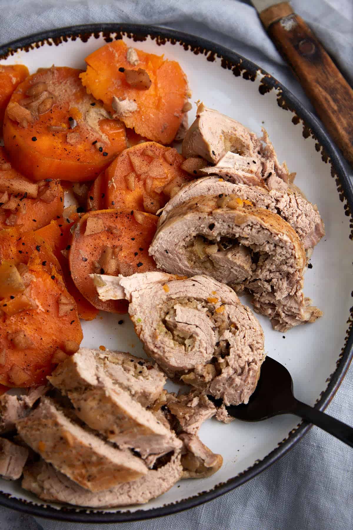 A serving fork removing slices of slow cooked pork tenderloin.