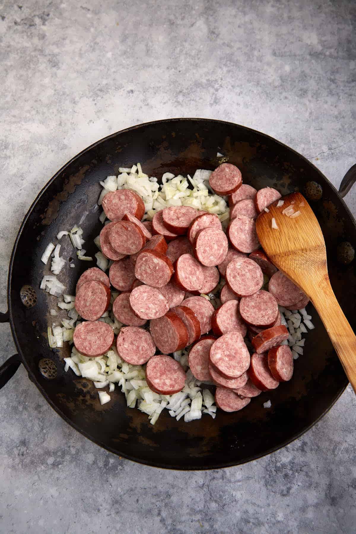 Onions and sausages in a skillet.