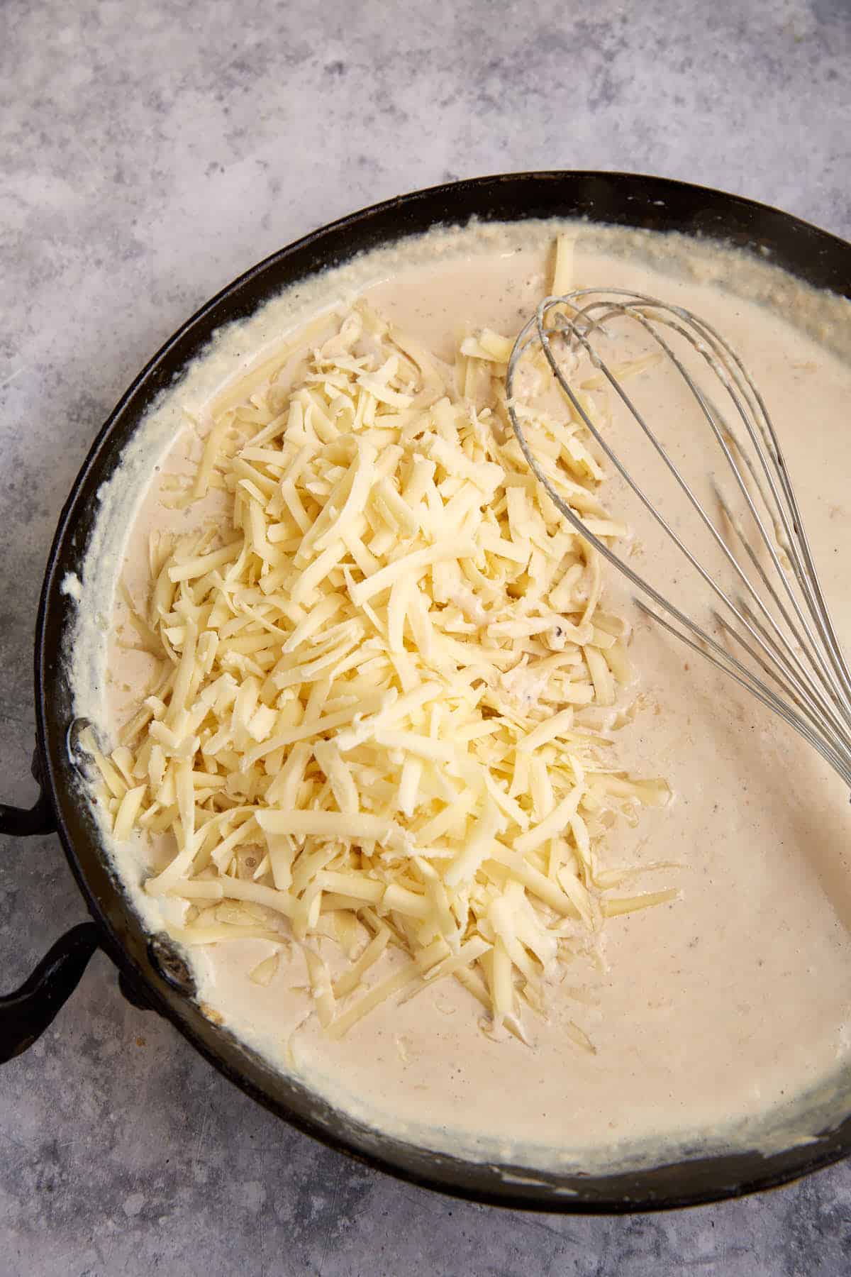A skillet of sauce with cheese added.
