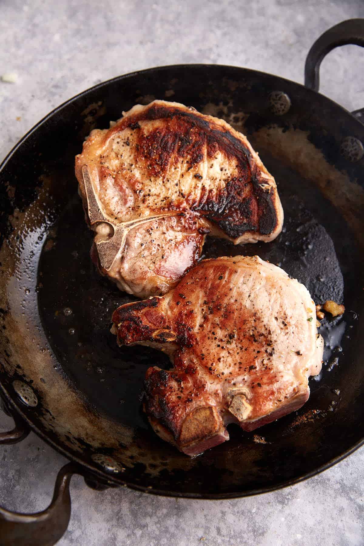 Browned pork chops in a skillet.