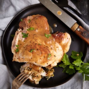 A pork chop with stuffing on a plate with a fork.