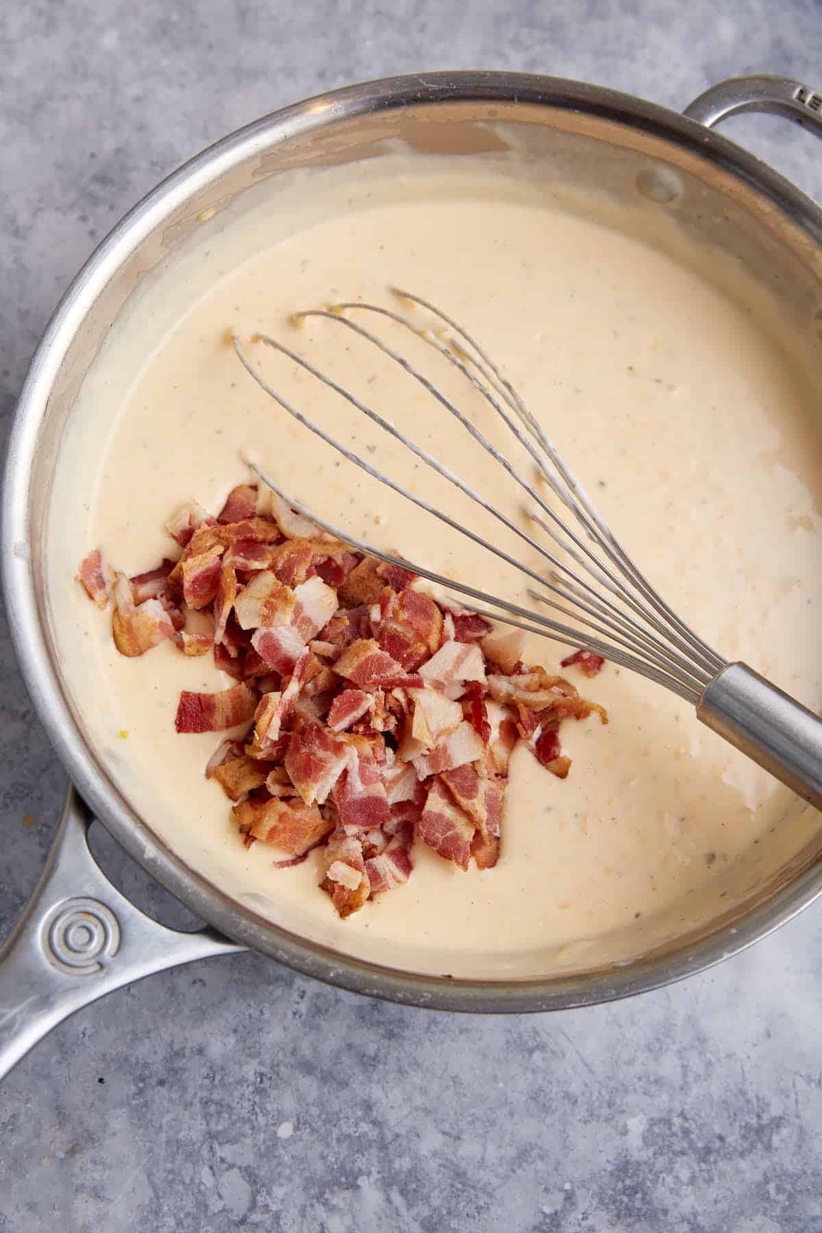 A saucepan with ranch sauce with bacon added.