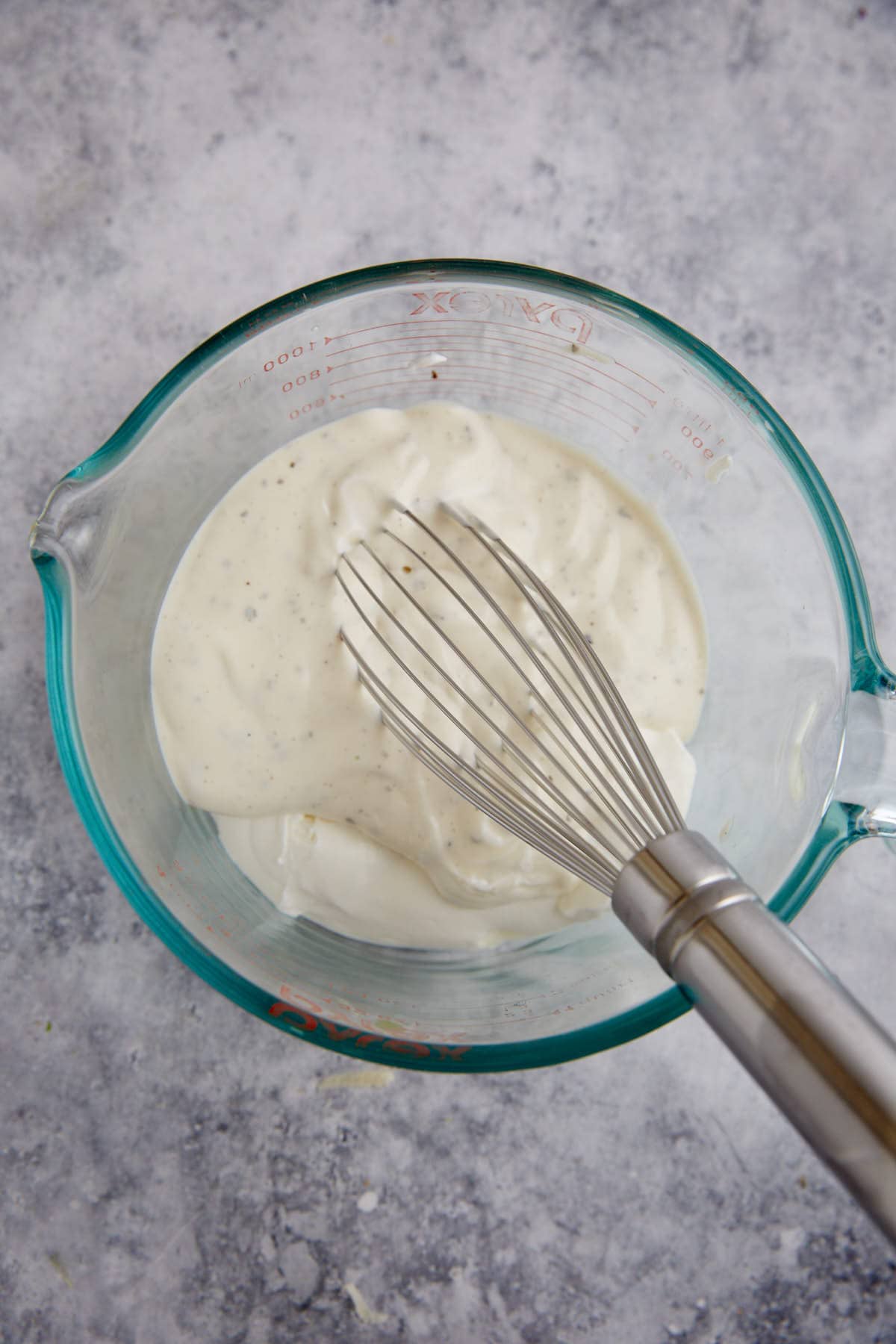 Sour cream and mayo in a bowl with a whisk.