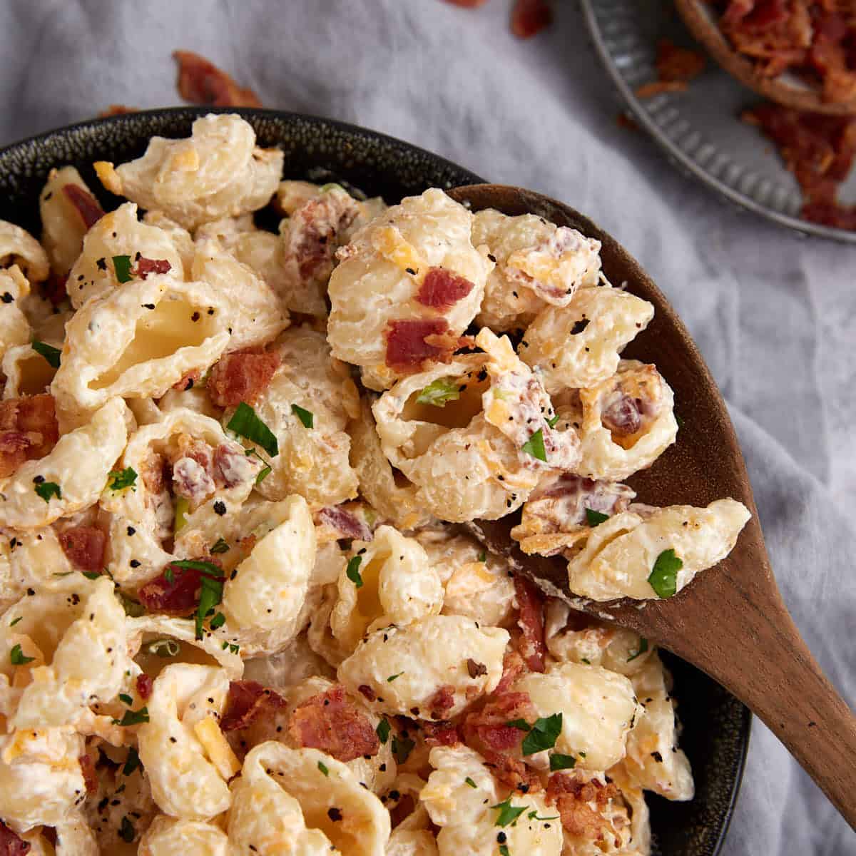 A wooden spoon in a bowl of ranch pasta salad.