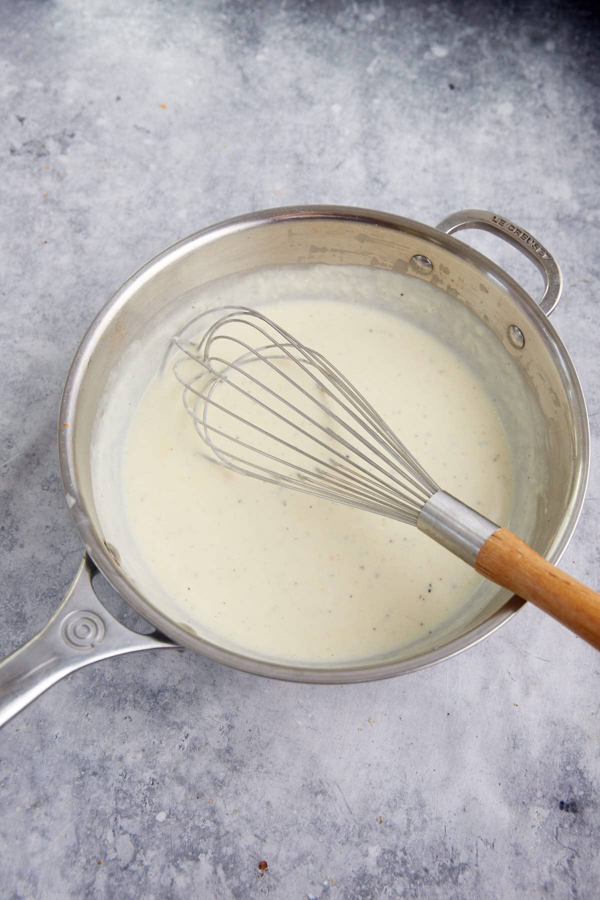 A whisk in a white sauce.