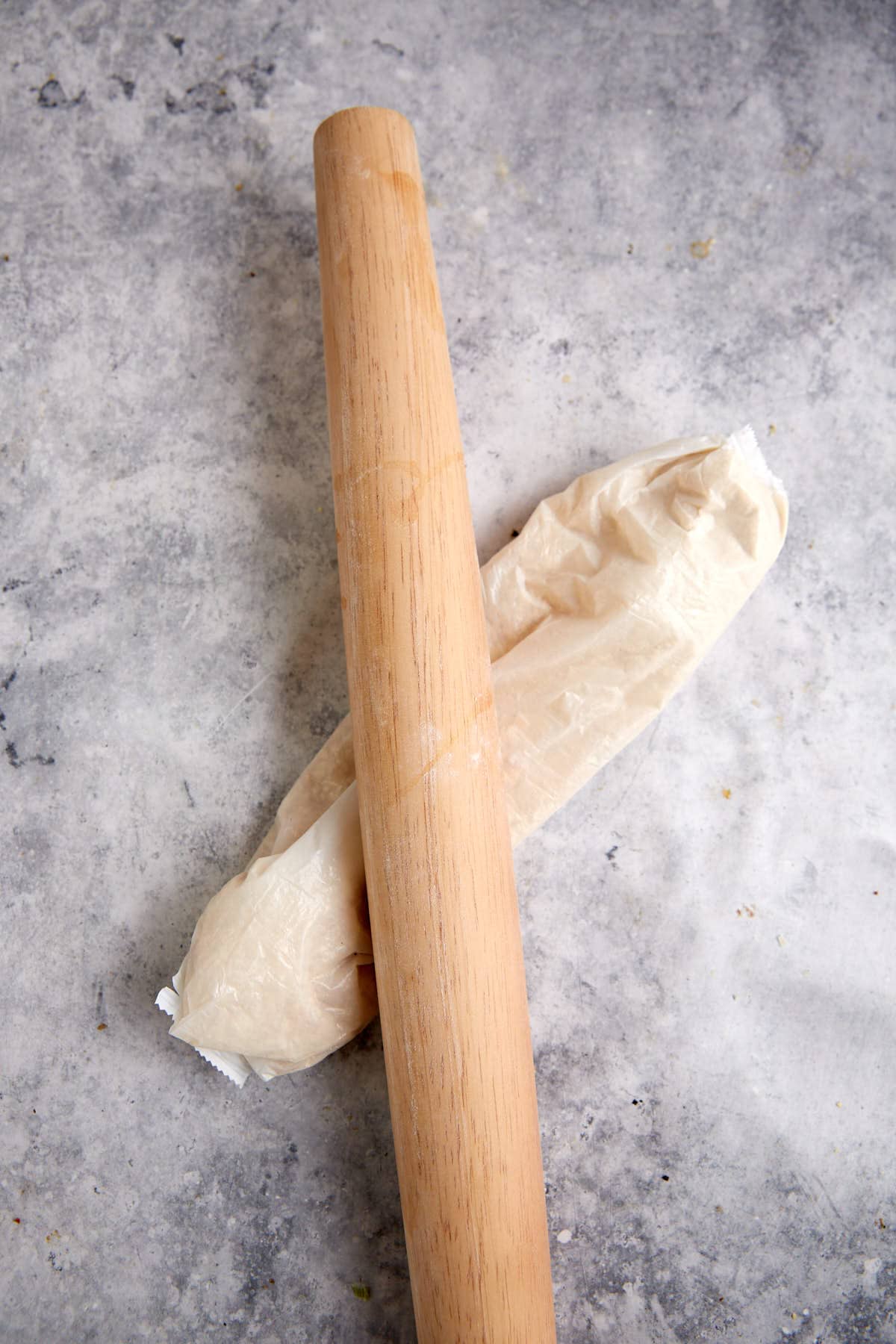 A sleeve of crackers being crushed with a rolling pin.
