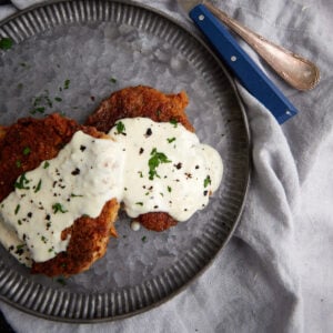 A plate with chicken fried steak covered in gravy.