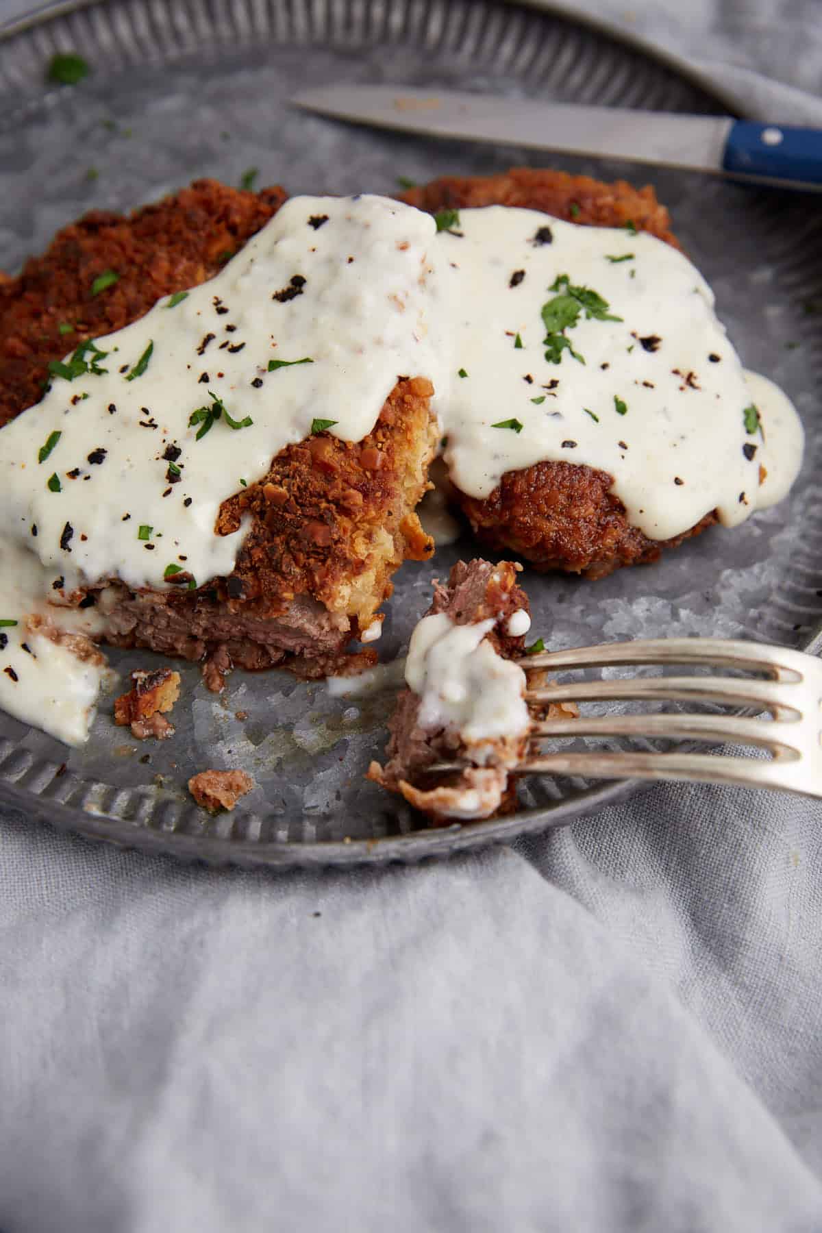 A bite of chicken fried steak on a fork.