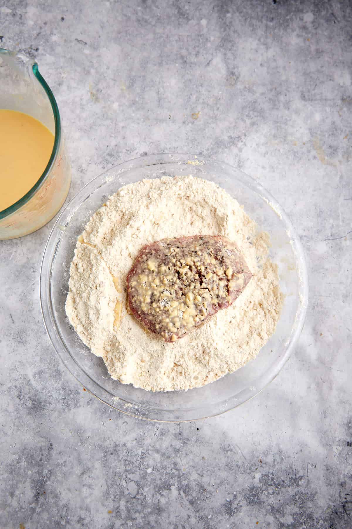 An initial coating of cracker crumbs on a steak.