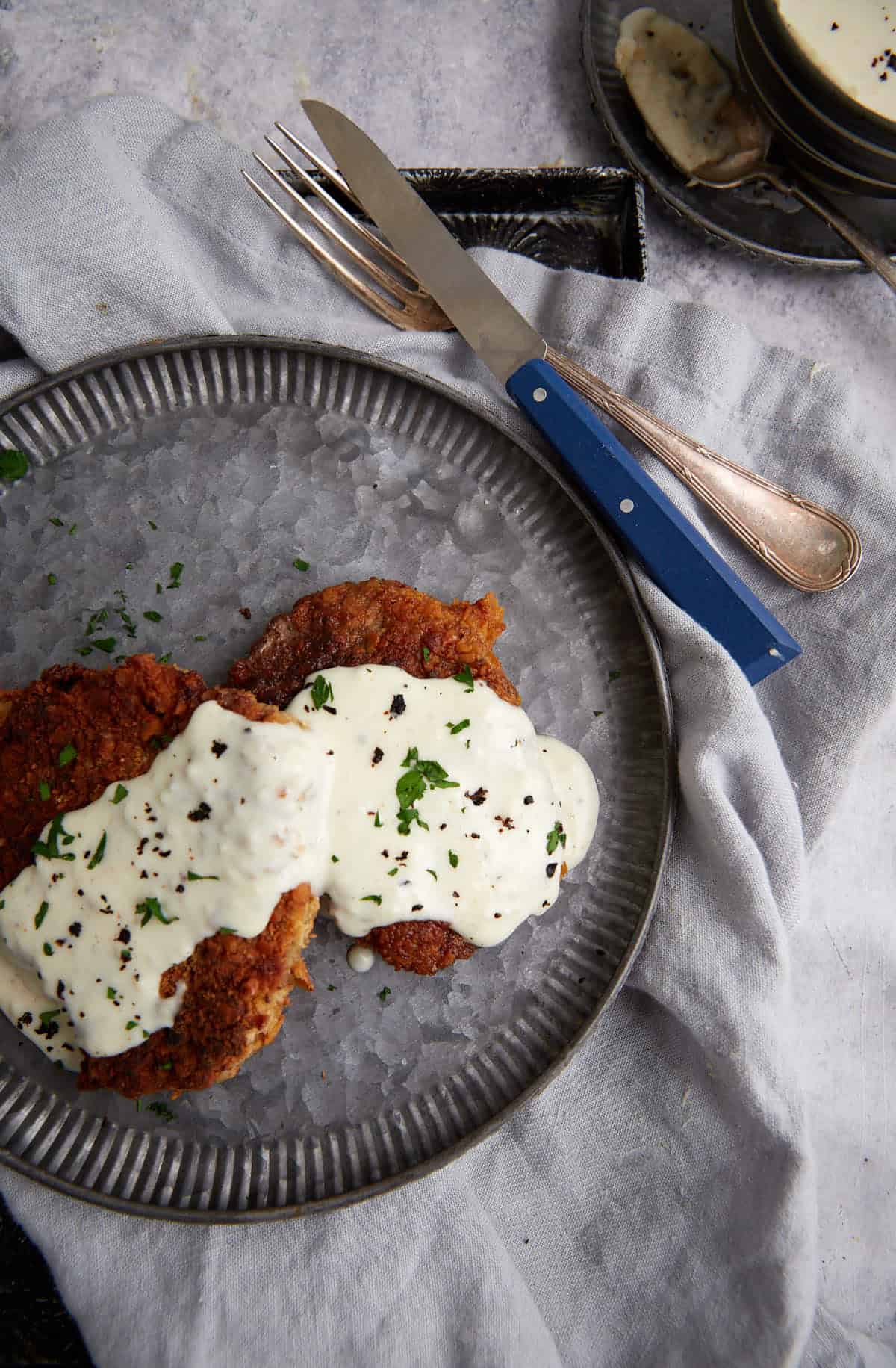 Two steaks next to a bowl of gravy.