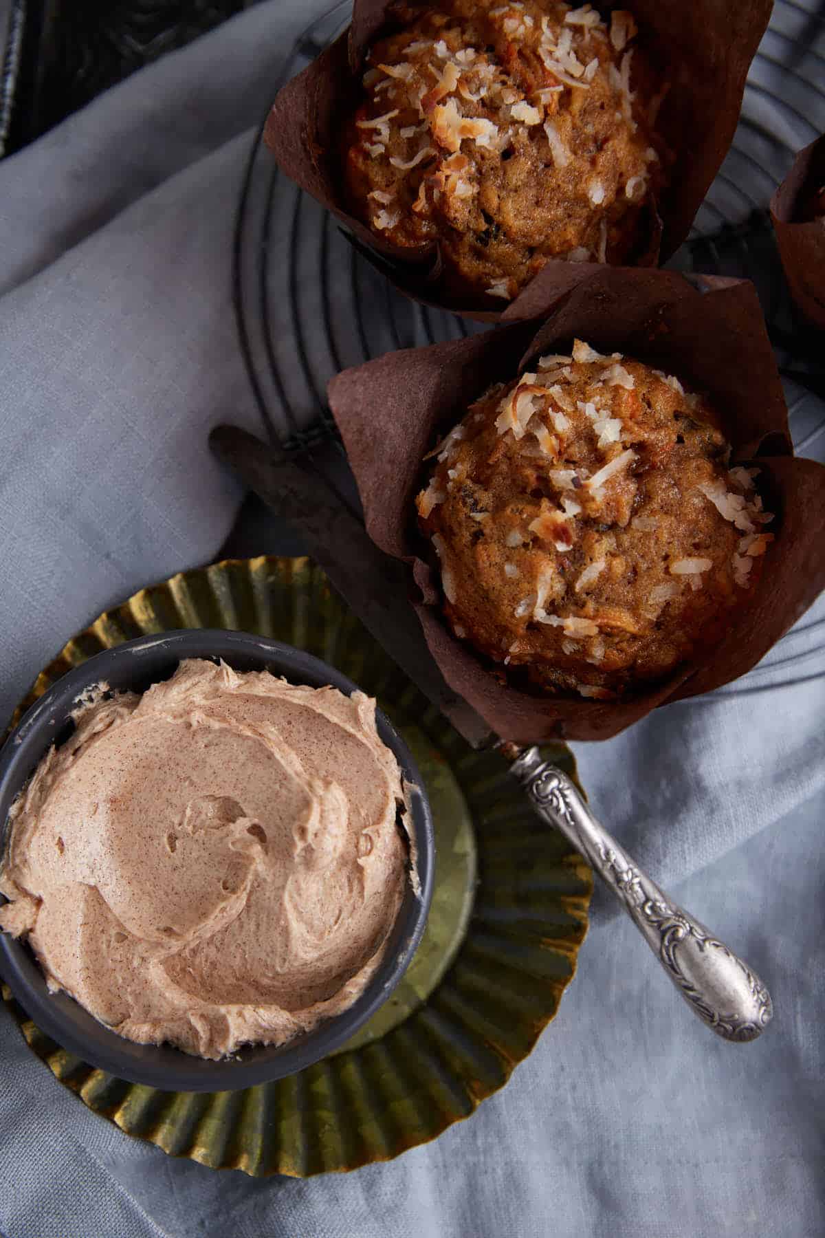 A bowl of cinnamon butter next to two muffins.