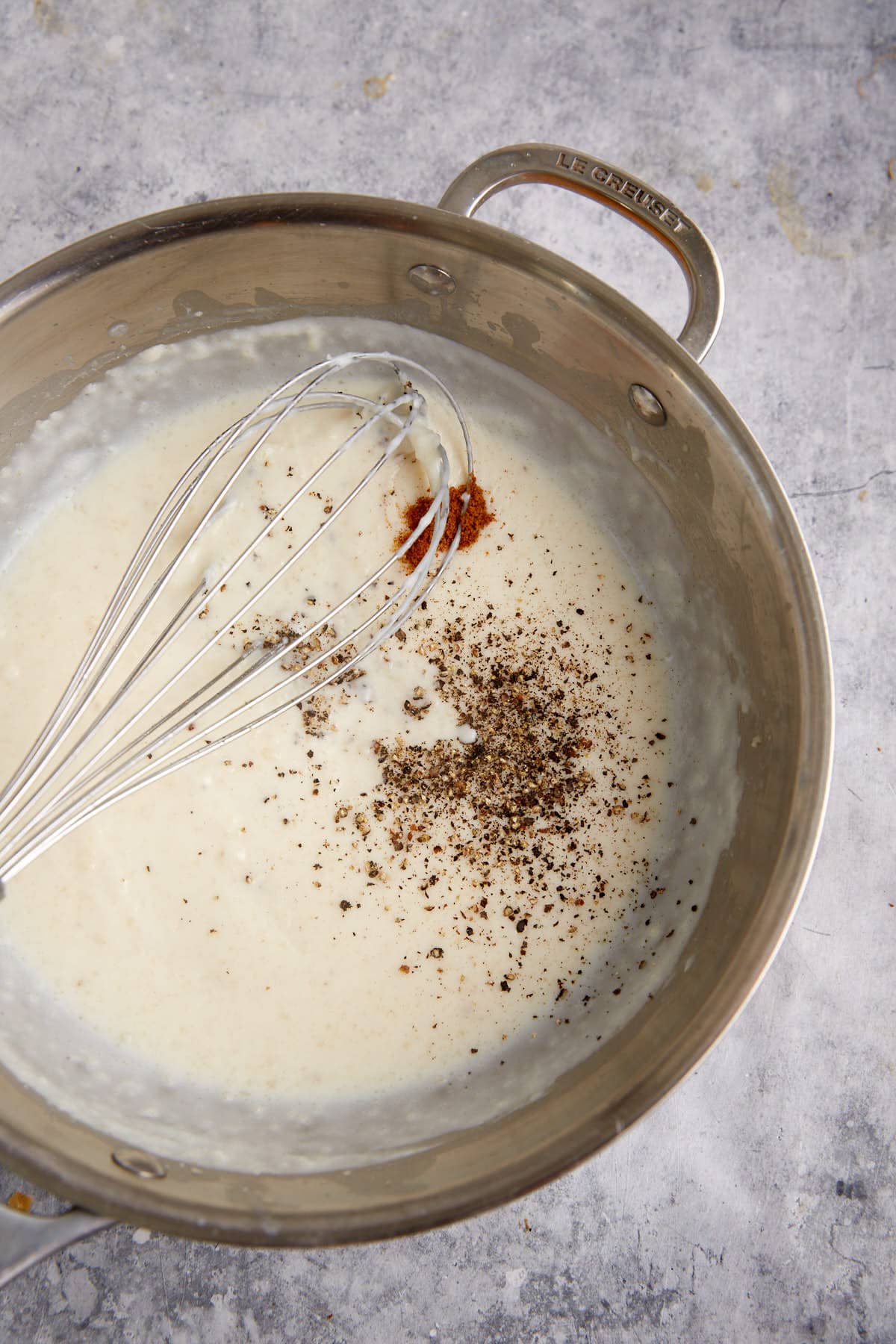 A whisk in a saucepan with gravy.