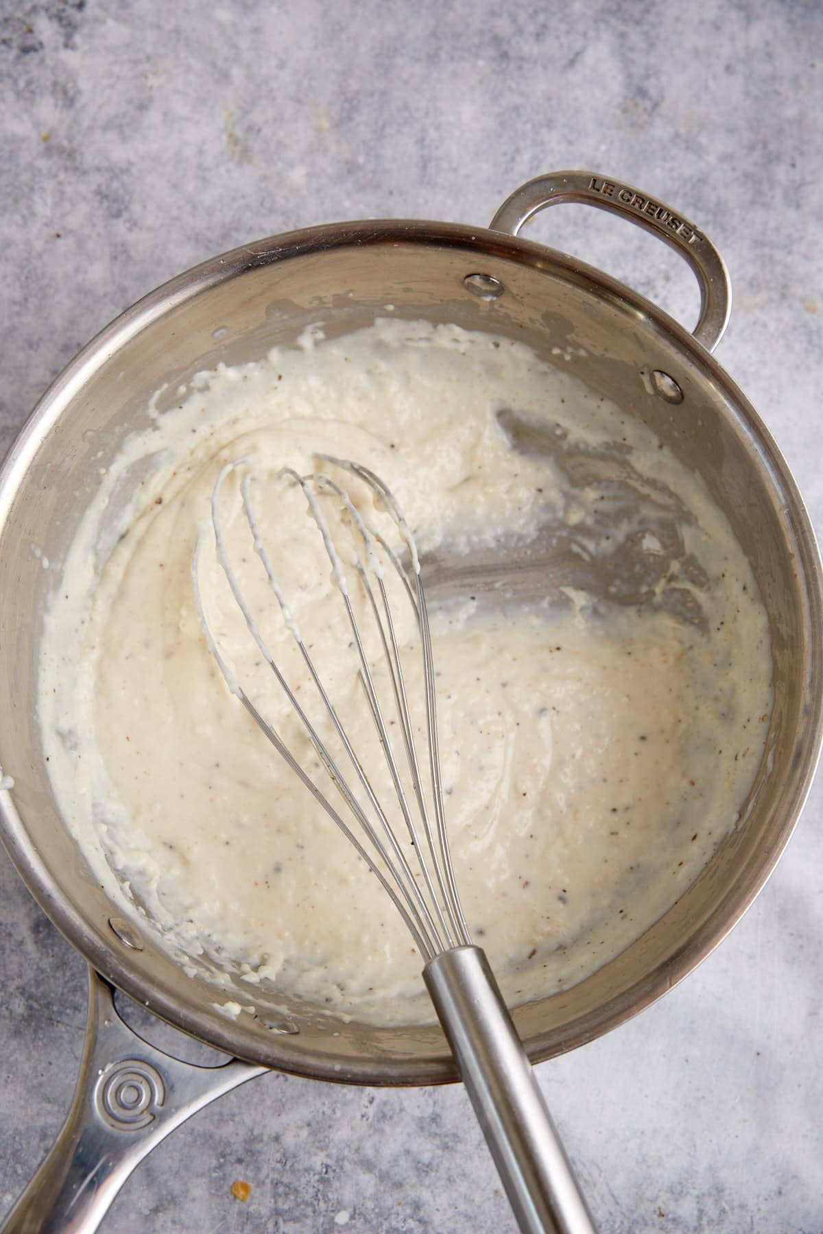 A saucepan and whisk with milk gravy.
