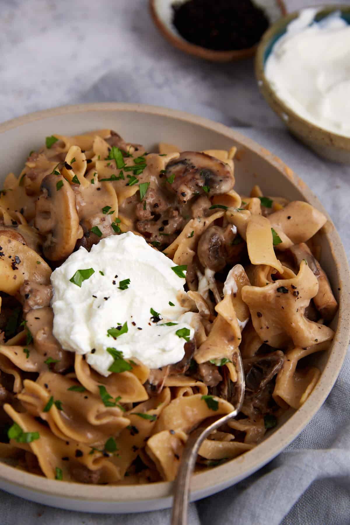 A bowl of beef stroganoff topped with sour cream.