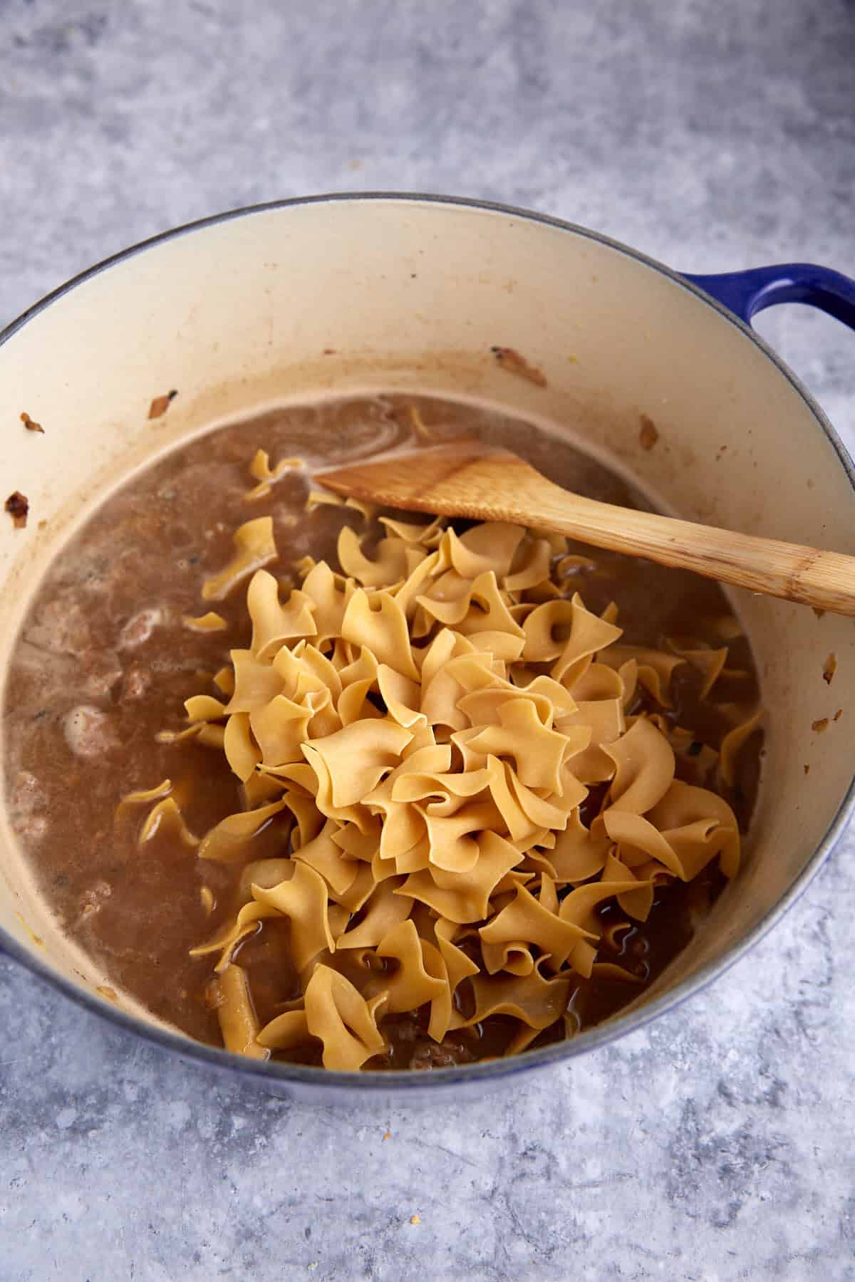 Noodles added to a pot of sauce.