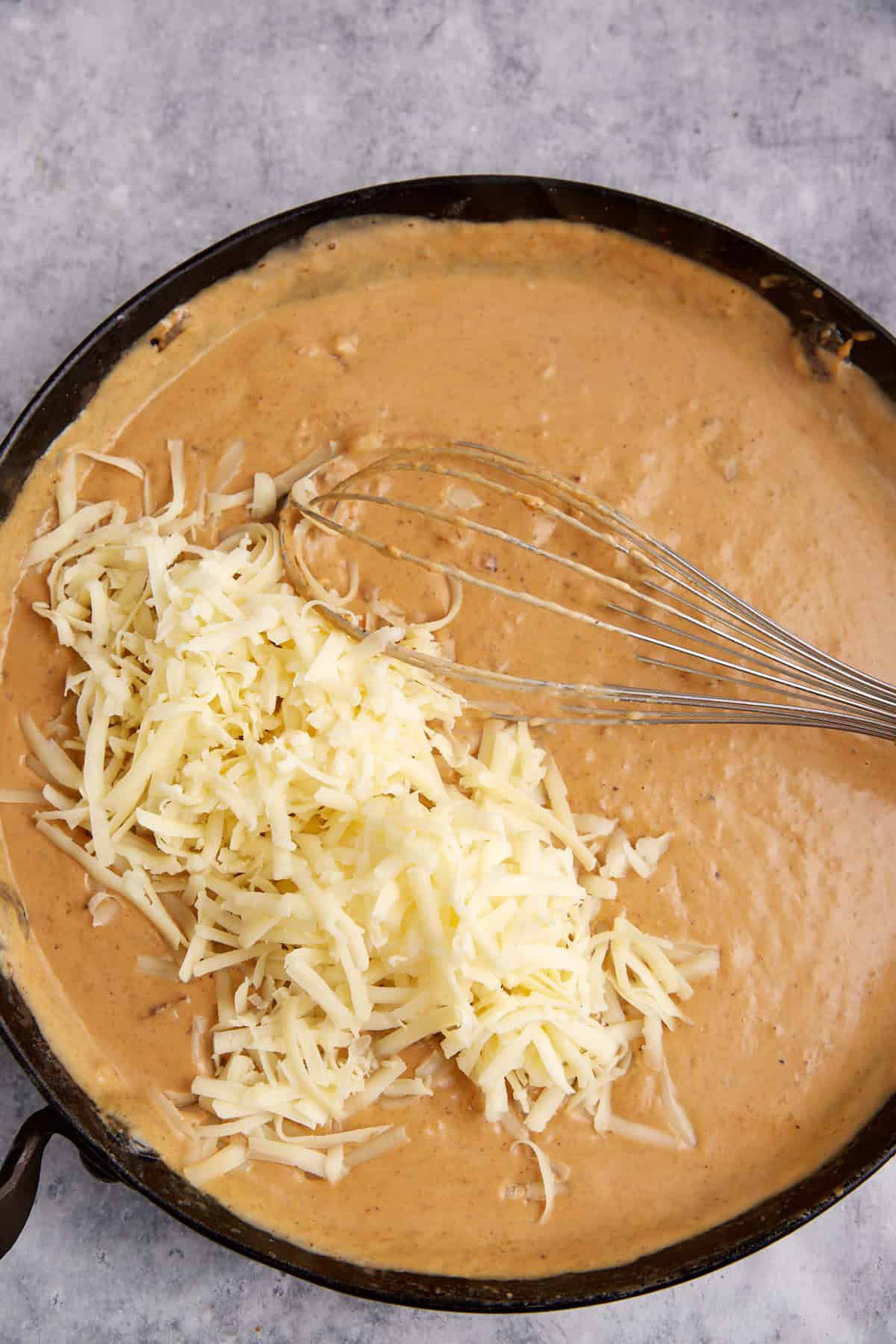 Cheese added to the sauce in a skillet.