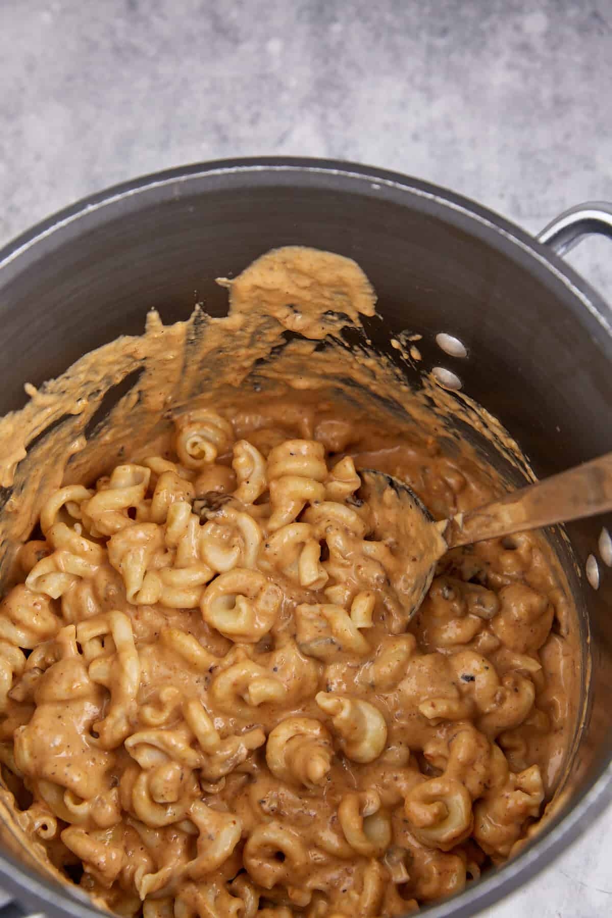 Cheesy sauce poured over pasta in a pot.