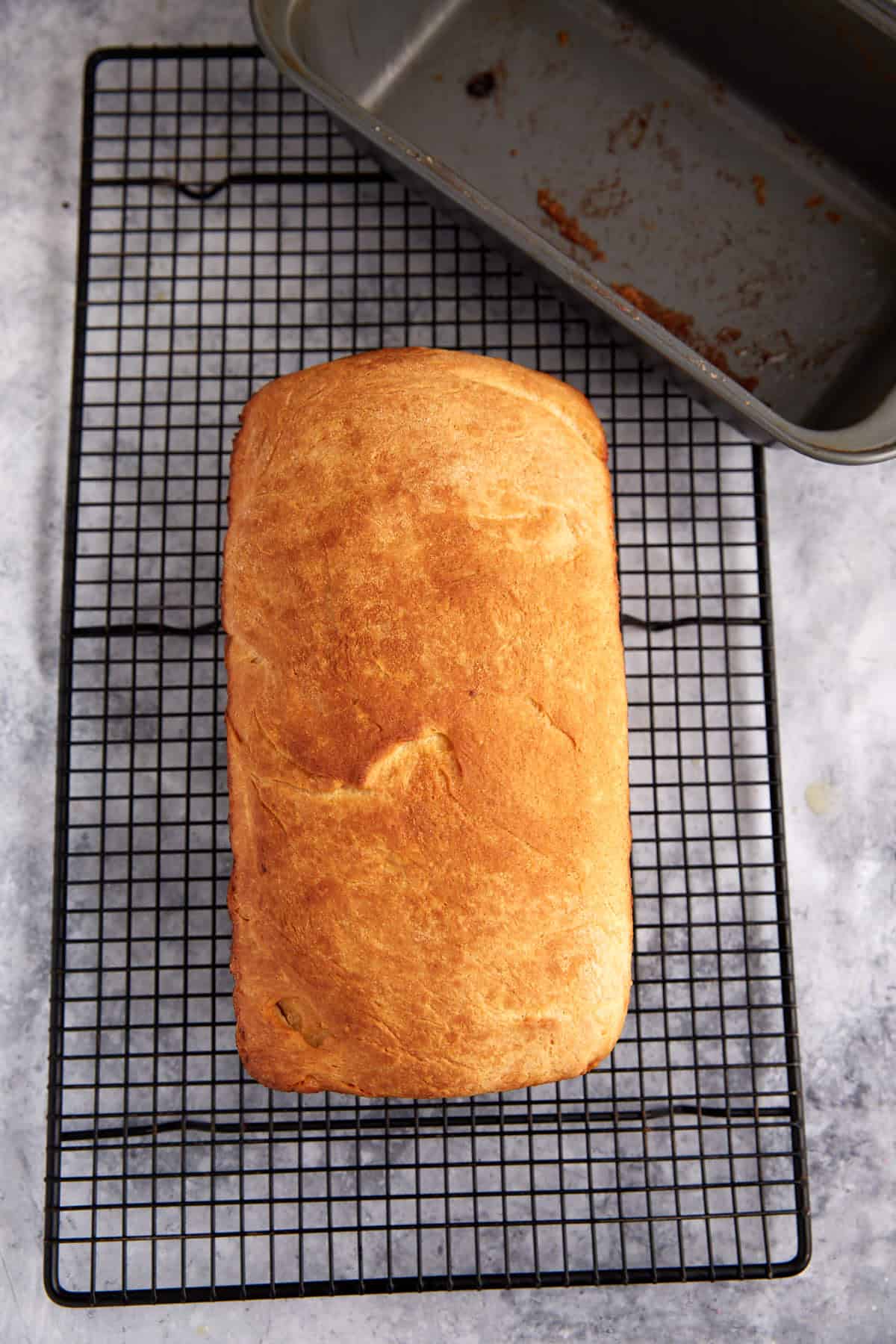 A loaf of cinnamon raisin bread on a cooling rack.