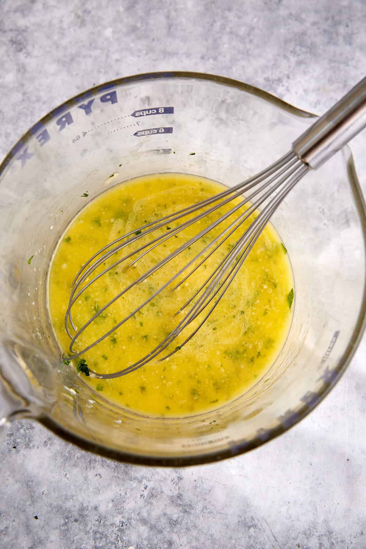 A bowl of garlic butter with a whisk.