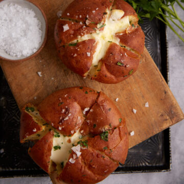 Two garlic rolls filled with cream cheese next to flaky salt.