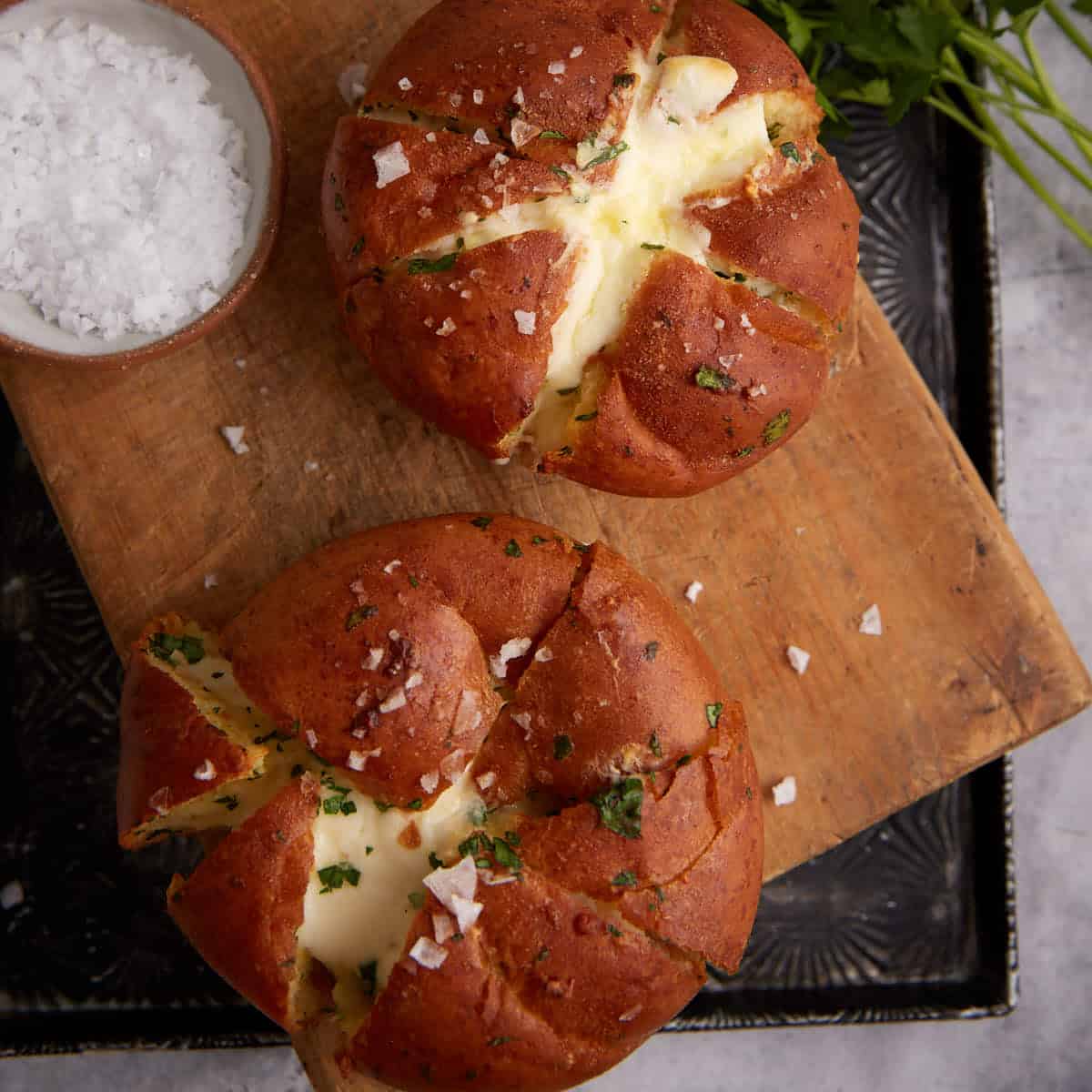 Two garlic rolls filled with cream cheese next to flaky salt.